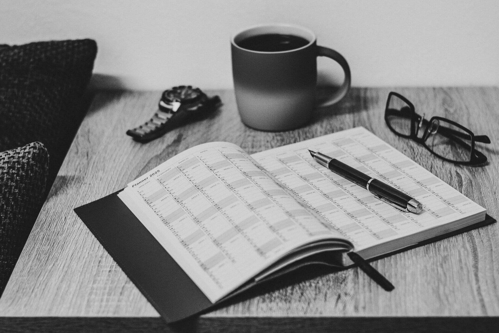 black and white desk scene with planner and coffee